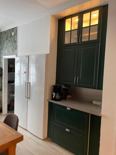 a kitchen with green cabinets and a white refrigerator at Villa Lyckan in Söråker