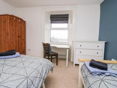 a bedroom with two beds and a desk and a window at 7 New Street in Sedbergh