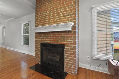 a brick fireplace in a living room with a window at Housepitality - The Victorian Vacation Home in Columbus