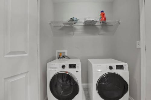 a laundry room with two washing machines and a shelf at Housepitality - The Victorian Vacation Home in Columbus