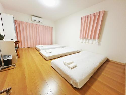 2 camas en una habitación con suelo de madera en Guesthouse Atelier Ten 民泊アトリエ天, en Osaka