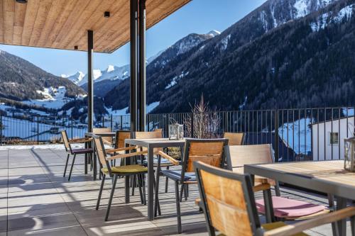 a patio with tables and chairs with mountains in the background at Stoana Apt 4-2 in San Giacomo