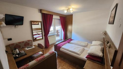 a small room with a bed and a mirror at Inter Hotel B&B in Vigo di Fassa