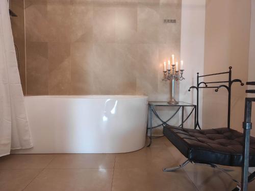 eine Badewanne in einem Zimmer mit einem Stuhl und Kerzen in der Unterkunft Villa Toscana Luxury Loft in Bolesławiec