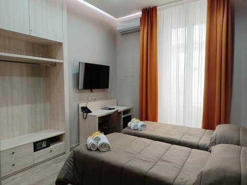 um quarto de hotel com duas camas e uma televisão em Schilizzi Hotel em Nápoles
