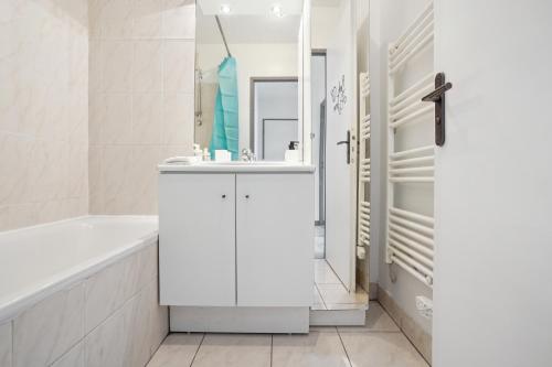 a white bathroom with a tub and a sink at Appartement Chic avec terrace et parking in Sartrouville