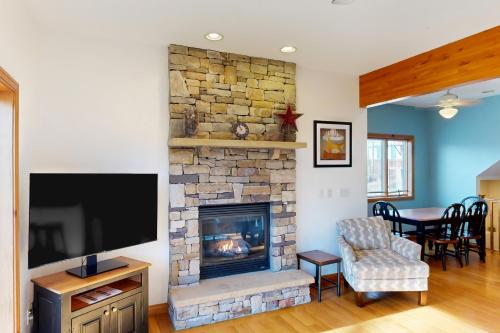 a living room with a stone fireplace and a tv at Slopeslide Lakehouse in McHenry