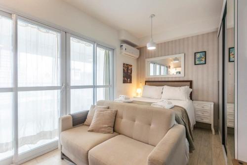 1 dormitorio con cama, sofá y espejo en BHomy Pinheiros Moderno e confortável CR134, en São Paulo
