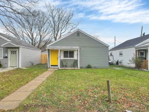 a house with a yellow door in a yard at Housepitality - The Southern Orchards Cottage in Columbus