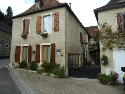 a house with brown shuttered windows and a gate at Chez Bouju in Castetnau-Camblong