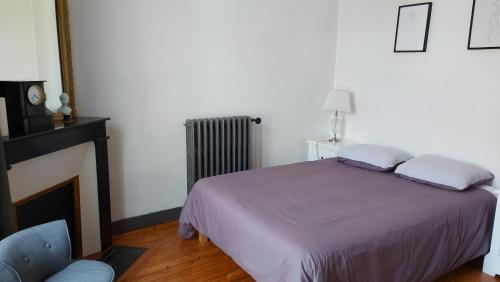 a bedroom with a bed and a fireplace and a chair at La petite escapade Féroise in Fère-en-Tardenois