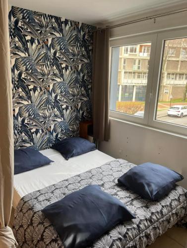 - une chambre avec 2 lits dotés d'oreillers bleus et d'une fenêtre dans l'établissement Au coeur de boulogne sur mer, à Boulogne-sur-Mer