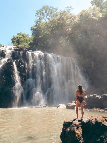 a woman standing on a rock in front of a waterfall at Reserva Natural Iguazú - Posada Puerto Bemberg in Puerto Libertad