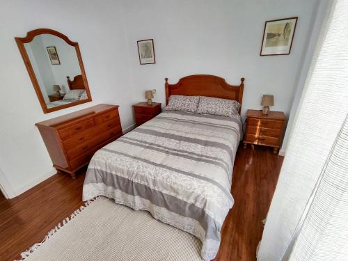 a bedroom with a bed and two dressers and a mirror at Apartamento Pena Furada in Ribadeo