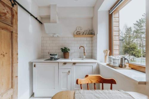 a kitchen with white cabinets and a sink and a window at Kresy Wschodnie in Okszów