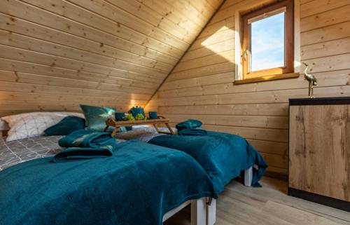 a bedroom with three beds in a wooden cabin at Ostoja Lemany - domki na Kaszubach, sauna, balia-jacuzzi, plac zabaw, tyrolka , dwa boiska, miejsce na ognisko, grill gazowy in Lemany