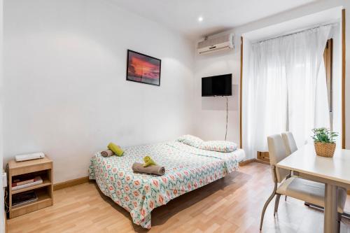 a small bedroom with a bed and a table and a desk at Atocha - Acogedor apartamento, centro de Madrid in Madrid