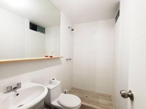 a white bathroom with a toilet and a sink at Apartamento Cielo Cajamarquino in Cajamarca