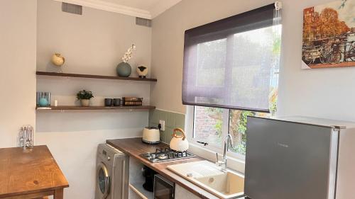 a kitchen with a sink and a refrigerator and a window at Traveller's Inn - Studio Cottage in Walmer