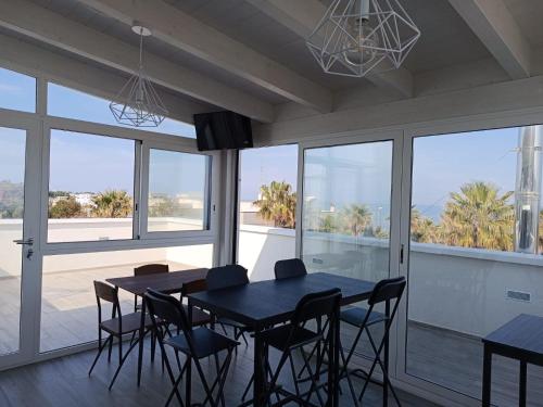 Un comedor con mesa y sillas y ventanas. en CASA AL MARE LUXURY, en Bari