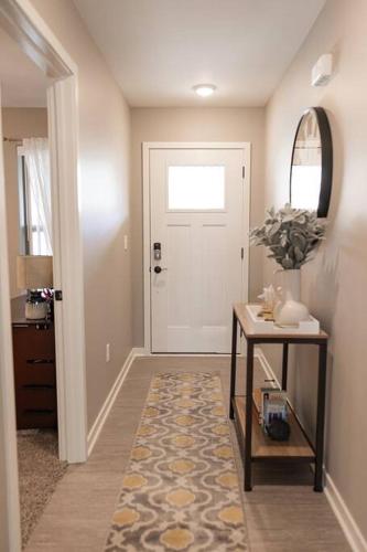 a hallway with a white door and a table with a rug at Newly Built 3 Bedroom Home in Loves Park in Loves Park
