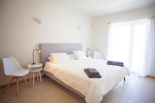 a white bedroom with a white bed and a chair at Casa Sol in Burgau