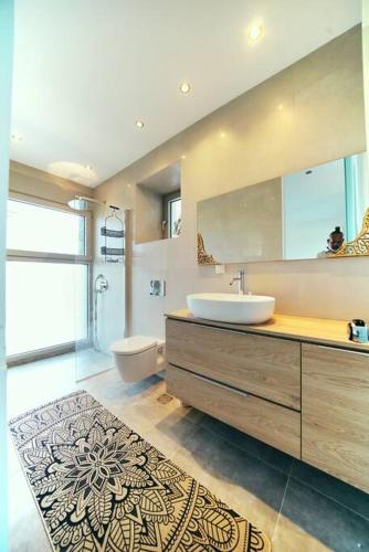 a bathroom with a sink and a toilet and a mirror at La Bella Villa - Cliffside Infinity Pool and Sunsets in Melínta