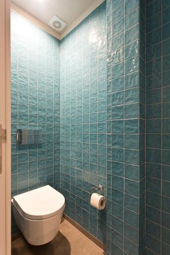 a bathroom with a toilet and a blue tiled wall at RVA - Gustave Eiffel Apartments in Porto