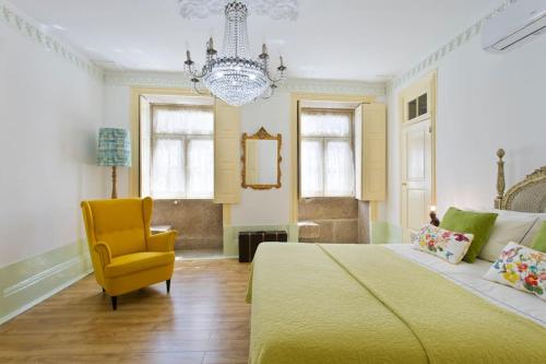 a bedroom with a bed and a chair and a chandelier at HC Villa Douro in Vila Nova de Gaia