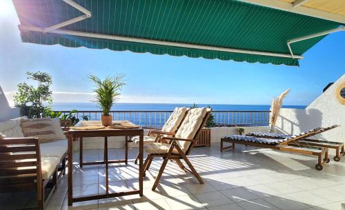 a patio with a table and chairs and the ocean at Ocean Wave in Acantilado de los Gigantes