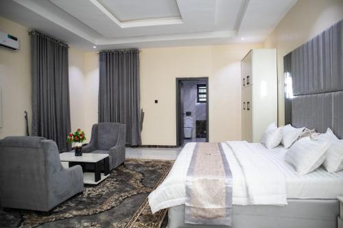 een slaapkamer met een groot wit bed en 2 stoelen bij Pula Pula Luxury Hotel and Suites in Karewa
