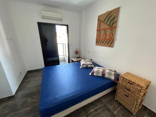 a bedroom with a large blue bed in a room at Novo Flat Capitania Varan in Guarujá
