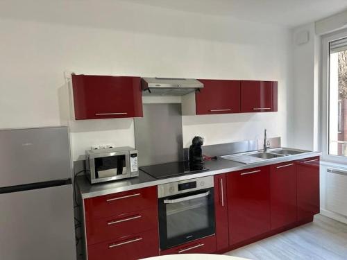 une cuisine avec des armoires rouges et un micro-ondes dans l'établissement Appartement Dunkerque, à Dunkerque