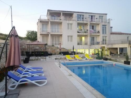 a swimming pool with lounge chairs and a building at Каравана под наем с невероятна морска панорама in Balchik