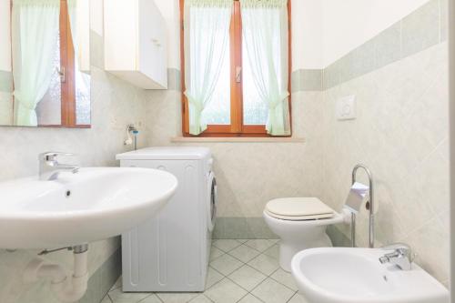 a white bathroom with a sink and a toilet at La Casetta di Procchio by HelloElba in Procchio