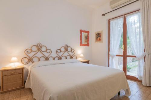 a bedroom with a large white bed and a window at La Casetta di Procchio by HelloElba in Procchio