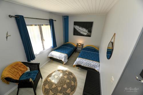 1 dormitorio con 2 camas, silla y ventana en Domaine les Rousselieres, en Olonne-sur-Mer