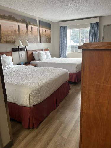 a hotel room with two beds and a window at Days Inn by Wyndham Turlock in Turlock