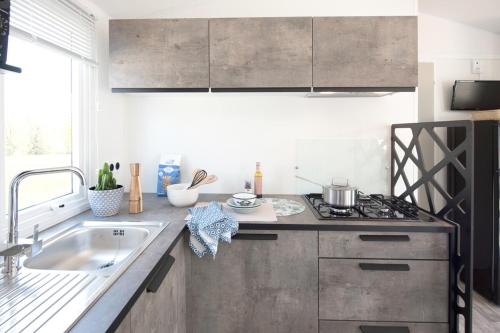 une cuisine avec un évier et une cuisinière dans l'établissement Chalet Bord de Mer, à Gouville-sur-Mer