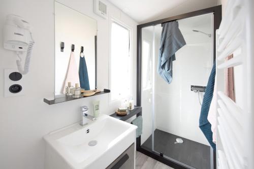 une salle de bain blanche avec un lavabo et une douche dans l'établissement Chalet Bord de Mer, à Gouville-sur-Mer