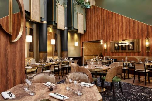 a restaurant with wooden walls and tables and chairs at Nest Hotel Paris la Défense - MGallery Collection in Puteaux