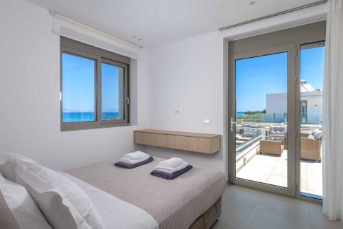 a white bedroom with a bed and a balcony at Villa Panaxia Votsalo in Theologos