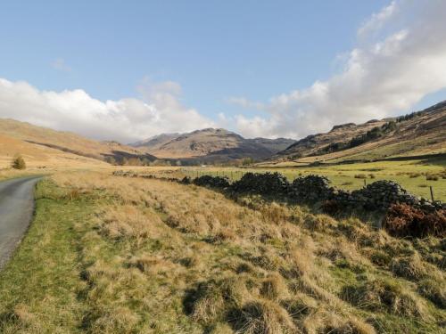 a road in a field with mountains in the background at Eden Vale in Broughton in Furness