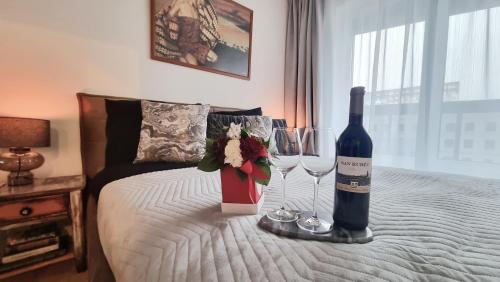 a bed with a bottle of wine and two glasses at NOWY Apartament Pełen Życia in Białystok