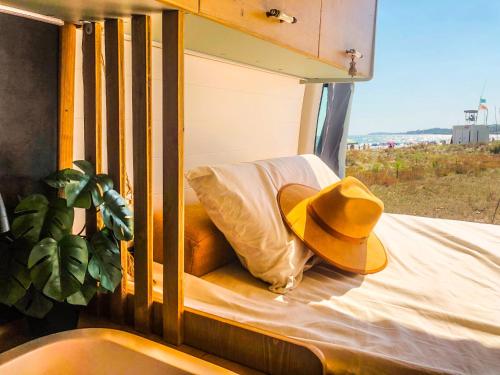 Furgoneta camperizada في بلايا ذي لاس أميريكاس: قبعة راعي بقر جالسة على سرير مع نافذة