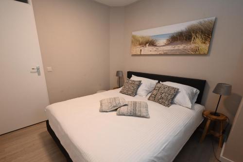 1 dormitorio con 1 cama blanca y 3 almohadas en Duingras, Résidence Deurloo 53-05, en Cadzand
