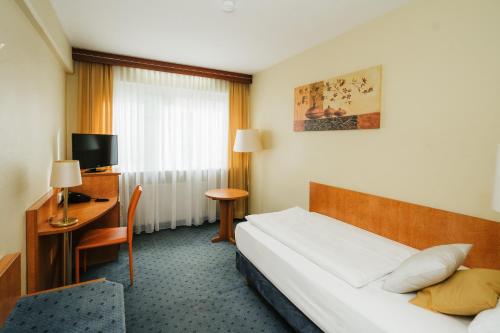 Habitación de hotel con cama y escritorio en Savoy Hotel, en Frankfurt