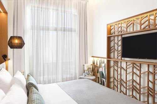 a hotel room with a bed and a flat screen tv at Wyndham Grand Crete Mirabello Bay in Agios Nikolaos