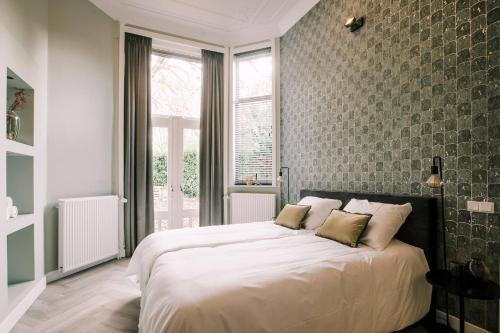 a bedroom with a large white bed with two pillows at Luxurious Apartment With Garden Hendrik's in Tilburg