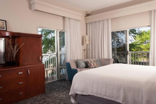 a bedroom with a bed and a chair and windows at Courtyard Charleston Waterfront in Charleston